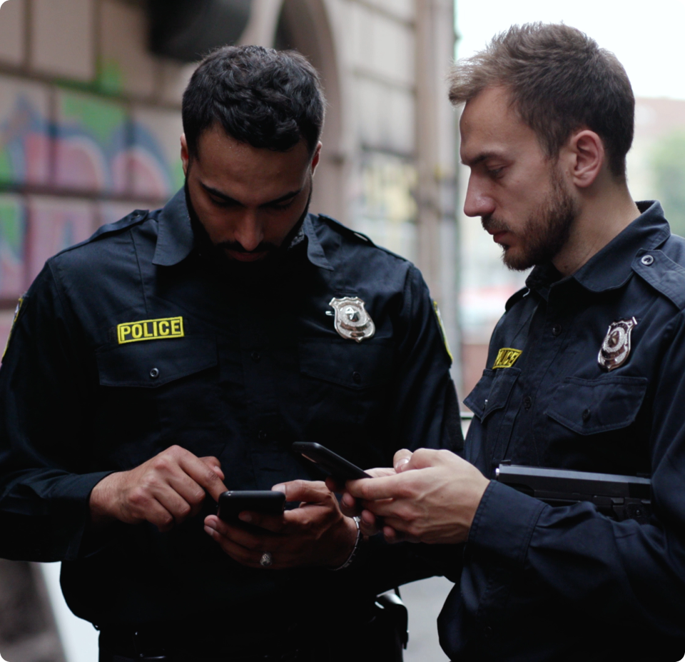 Two corrections officers looking at their devices together